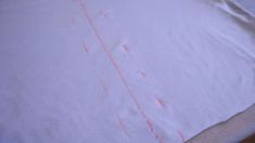 a white shirt with red lines on it sitting on top of a wooden table next to a knife