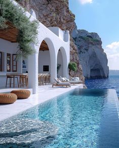 an outdoor swimming pool with chaise lounges next to the water and cliffs in the background