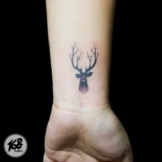 a small deer head tattoo on the wrist