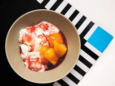 a bowl filled with ice cream and peaches on top of a striped place mat