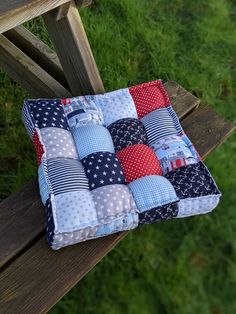 a patchwork pillow sitting on top of a wooden bench