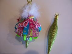 two christmas ornaments hanging on the wall next to a green tree ornament with white feathers