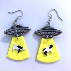 pair of earrings with black and white dog in an alien saucer on yellow background