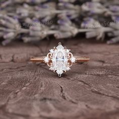 a close up of a ring on top of a piece of wood with flowers in the background