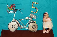 a baby is sitting next to a metal bike