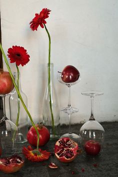 there are many different vases with flowers and fruit in them on the table next to each other