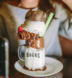 a woman sitting at a table in front of a cup filled with ice cream and chocolate