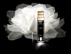 a white flower sitting on top of a black table next to a bottle of perfume