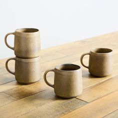 three coffee mugs sitting on top of a wooden table