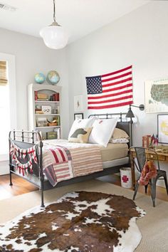 a bedroom with an american flag on the wall and cow hide rugs in front of the bed