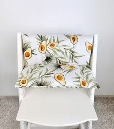 a white chair with an avocado print on the back and seat cover is sitting in front of a wall