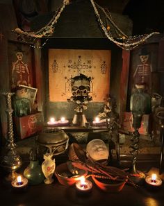 candles are lit in front of an altar with skulls and skeletons on it, along with other items