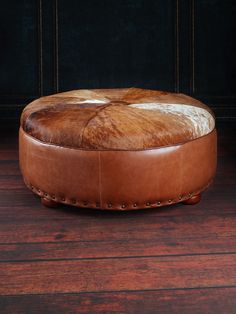 Western Sunset Cowhide Ottoman showcasing brown leather and brindle cowhide cushion, detailed with antiqued nail heads, on a wooden floor. Ottoman Inspiration, Western Sunset, Cowhide Ottoman, New House Living Room, Brindle Cowhide, Faux Cowhide, Bungalow Homes, Western Furniture, Custom Frames