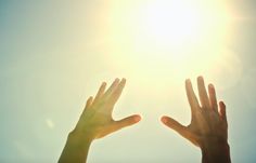 two hands reaching up towards the sun