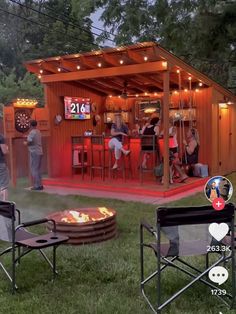 two people sitting in lawn chairs next to a fire pit with an outdoor bar on it