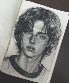 a drawing of a young man's face is shown in an open sketchbook