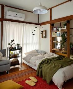 a bedroom with a bed, couch and bookshelf next to a large window