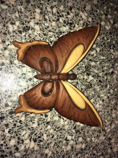 a wooden butterfly decoration sitting on top of a marble countertop next to a tile floor