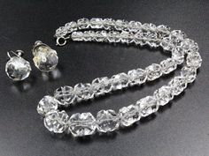 "DESCRIPTION: Transport yourself to the roaring 1920s with this exquisite antique jewelry set, a testament to the opulence of the Art Deco era. The necklace, a masterpiece of design, features a symphony of rock quartz crystal beads gracefully strung together and secured with a sterling silver clasp bearing the hallmark \"BB\" and \"STERLING.\" Complementing this timeless piece are the stud earrings, a perfect match to the necklace's elegance. In excellent condition, the set is an antique treasure, with a minor residue of glue delicately hinting at its rich history. The necklace, boasting a spring ring clasp, measures a dainty 16\" with beads ranging from 6mm to 12mm, while the earrings, secured with a screw-back clasp, exhibit a charming 15mm diameter. This Art Deco ensemble is a captivati Classic Jewelry With Diamond Cut Round Beads, Antique Jewelry For Vintage Events, Vintage Diamond Cut Necklace For Formal Occasions, Retro Round Necklace For Formal Occasions, Retro Round Necklaces For Formal Occasions, Vintage Diamond Cut Jewelry For Vintage Events, Vintage Diamond Cut Jewelry For Evening, Classic Diamond Cut Jewelry For Vintage Events, Art Deco Evening Jewelry With Jewels