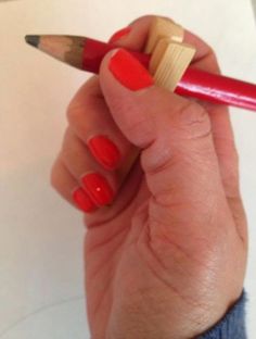 a person holding a red pencil in their left hand and the other hand has a yellow tip on it