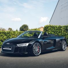 a black sports car parked in front of some bushes