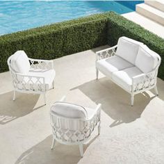 three white patio furniture sitting next to a swimming pool