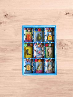 an open blue box filled with assorted items on top of a wooden floor next to a wall