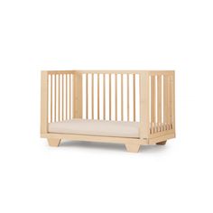 a small wooden crib with a cushion on the bottom and sides, against a white background