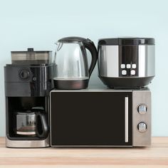 a microwave oven sitting on top of a counter next to a coffee pot and kettle