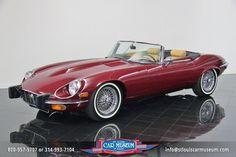 a red sports car is parked on a black tile floor in front of a white wall