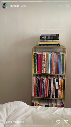 there is a book shelf with many books on it in the corner next to a bed