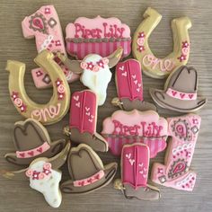 decorated cookies are arranged in the shape of cowboy hats and horseshoes with pink, brown and white frosting