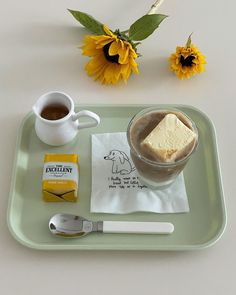 there is a cup of coffee and some sugar on the tray next to sunflowers