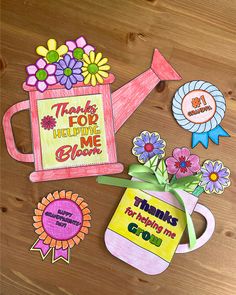 some flowers and stickers are on the table next to a watering can that says thanks for helping me grow