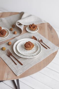 a table set for two with plates and silverware on it, including a muffin