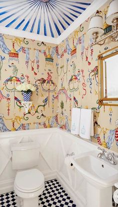 a bathroom with a white toilet sitting next to a bath tub under a blue and white ceiling