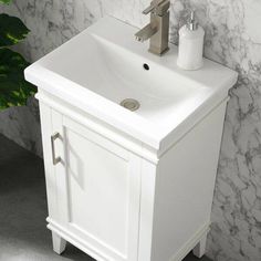 a white bathroom sink sitting next to a green plant