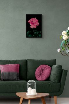 a living room with a green couch, pink pillows and a painting on the wall