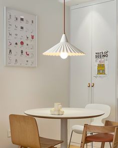 a white table with two chairs and a light hanging from the ceiling in a room