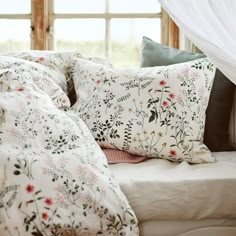 pillows and blankets on a bed in front of a window