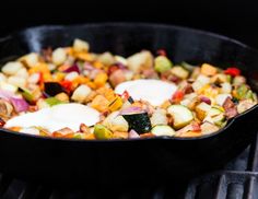 a skillet filled with vegetables cooking on an outdoor grill