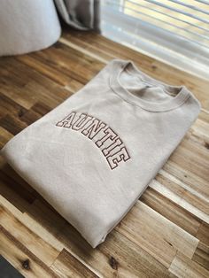 Us aunties/tias deserve a comfy and cozy sweatshirt too! Not an auntie?? Feel free to have a custom request for your sweatshirt! Just type it into the blank text box .🤍 This sweatshirt sports an athletic font that is giving cool aunt vibes. Throw this classic crew on and be ready to take on your exhausting day of being an auntie! Design measurements are roughly 7” long by 2.5” tall for sizes Small to XL. Sizes 2X - 4X have a design size of roughly 10" long by 4" tall. All sweatshirts are unisex One Word Sweatshirts, Auntie Era Sweatshirt, Auntie Embroidered Sweatshirt, Auntie Clothes, Aunt Goals, Cool Aunt Aesthetic, Auntie Outfits, Trending Sweatshirts, Aunt Vibes