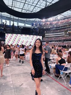 a woman standing in front of a large crowd at a sporting event with people sitting on the bleachers