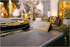 a table set with place cards, silverware and gold sequins on it