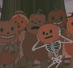 a group of pumpkins that are standing in front of a tree with faces drawn on them