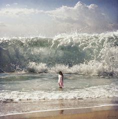 a person standing in the ocean with waves crashing behind them