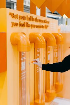 a woman pointing at some yellow machines in a room with orange walls and flooring