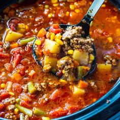 a ladle full of soup with meat and vegetables in it, ready to be eaten