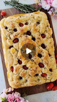 a square shaped pastry on a cutting board surrounded by flowers and greenery, with a video showing how to make it