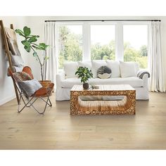 a living room with white furniture and wood flooring in front of a large window